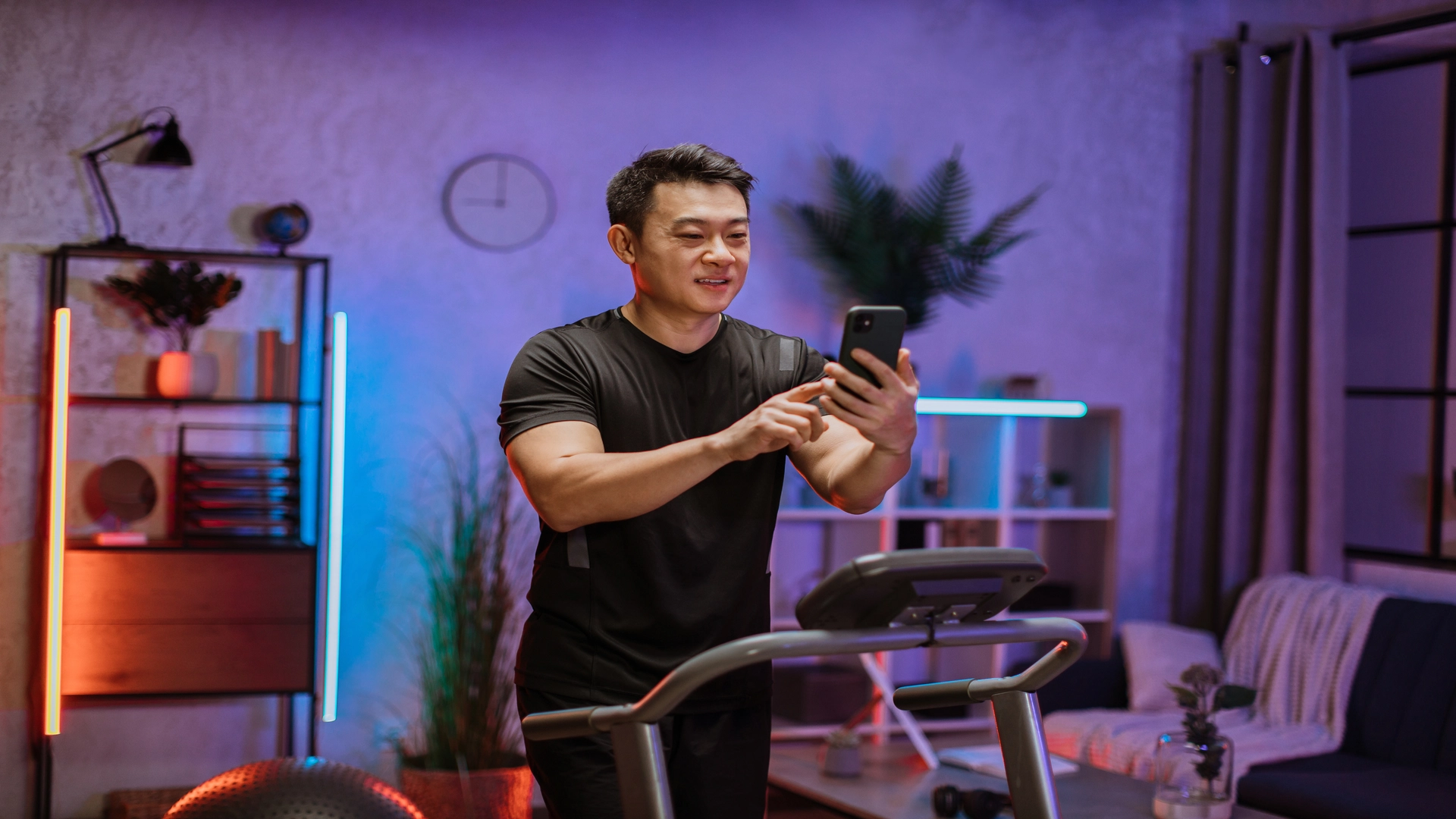 A man using his phone while doing exercise in a home gyms decorate wit elegant lights